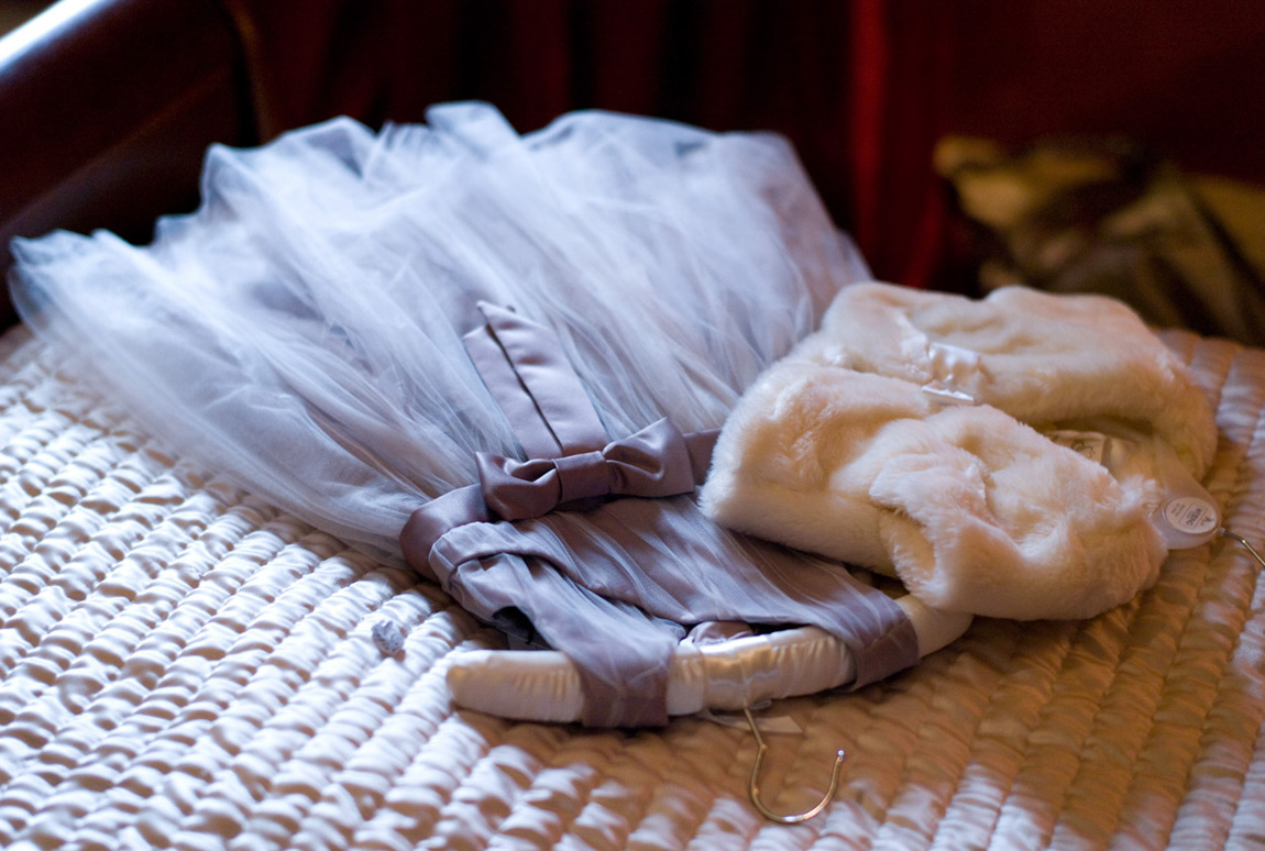 Captured in natural beautiful light - the little bridesmaid dress draped over the bed in the bridal suite.