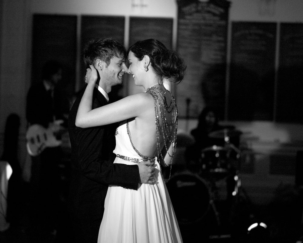Couple sharing their first dance, nose to nose under soft light in black and white.