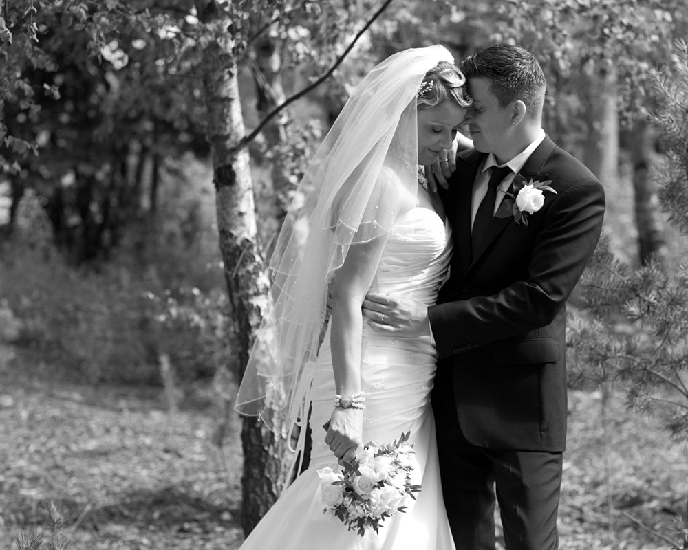 Couple stood together through woodland at the KP Club, captured in black and white.