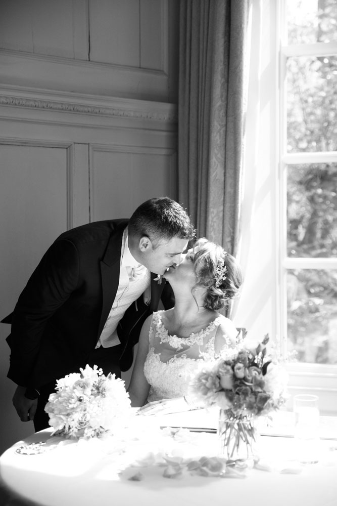 Newlyweds sharing a kiss after their ceremony, captured in black and white.