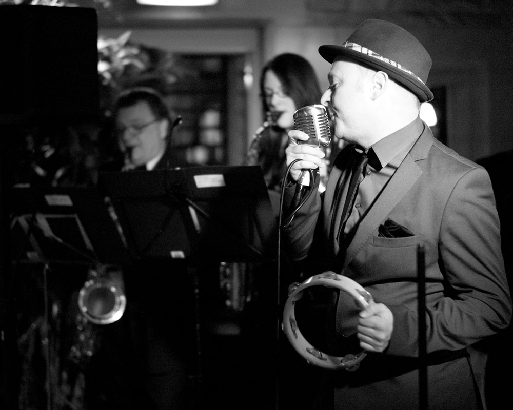 Live wedding singer performing as guests listen, captured in black and white.