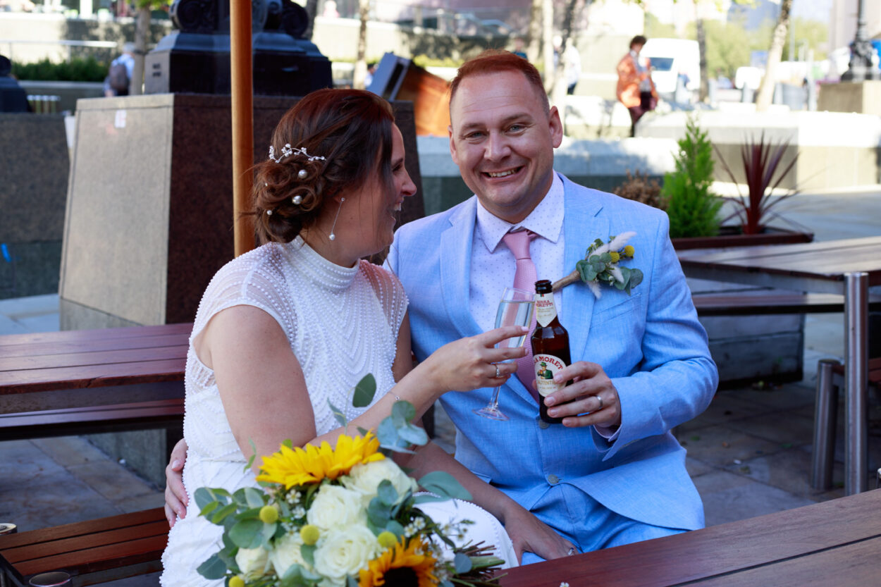 Bride and groom share a quiet laugh outside Leeds Civic Hall, captured naturally in soft evening light.