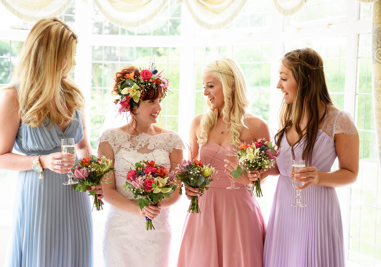 Natural moment of the bride and bridesmaids chatting with relaxed smiles before the ceremony.