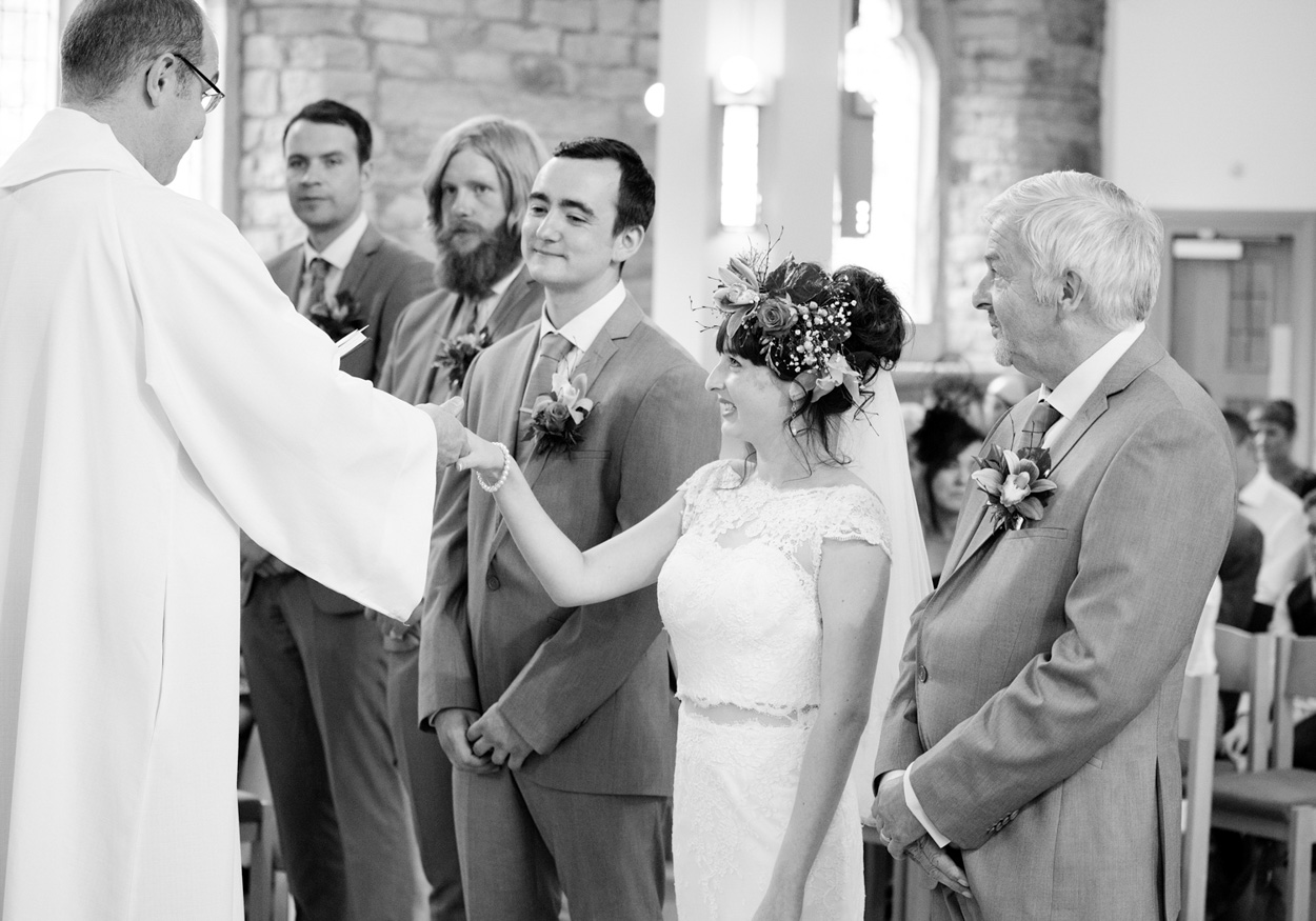Bride signs the register at St Paul’s Church as the groom smiles warmly at the camera.