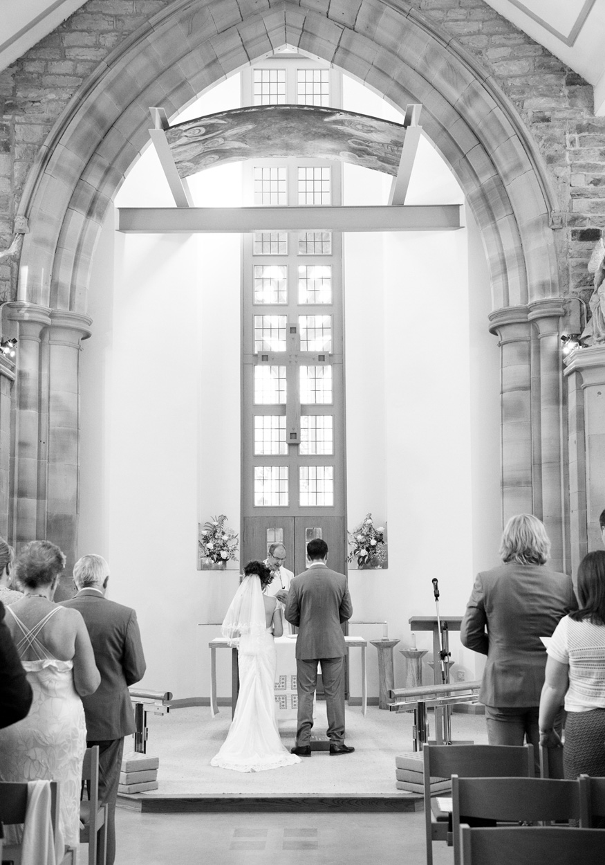Bride and groom face each other in soft light and shadow, church in the background at Armitage Bridge.