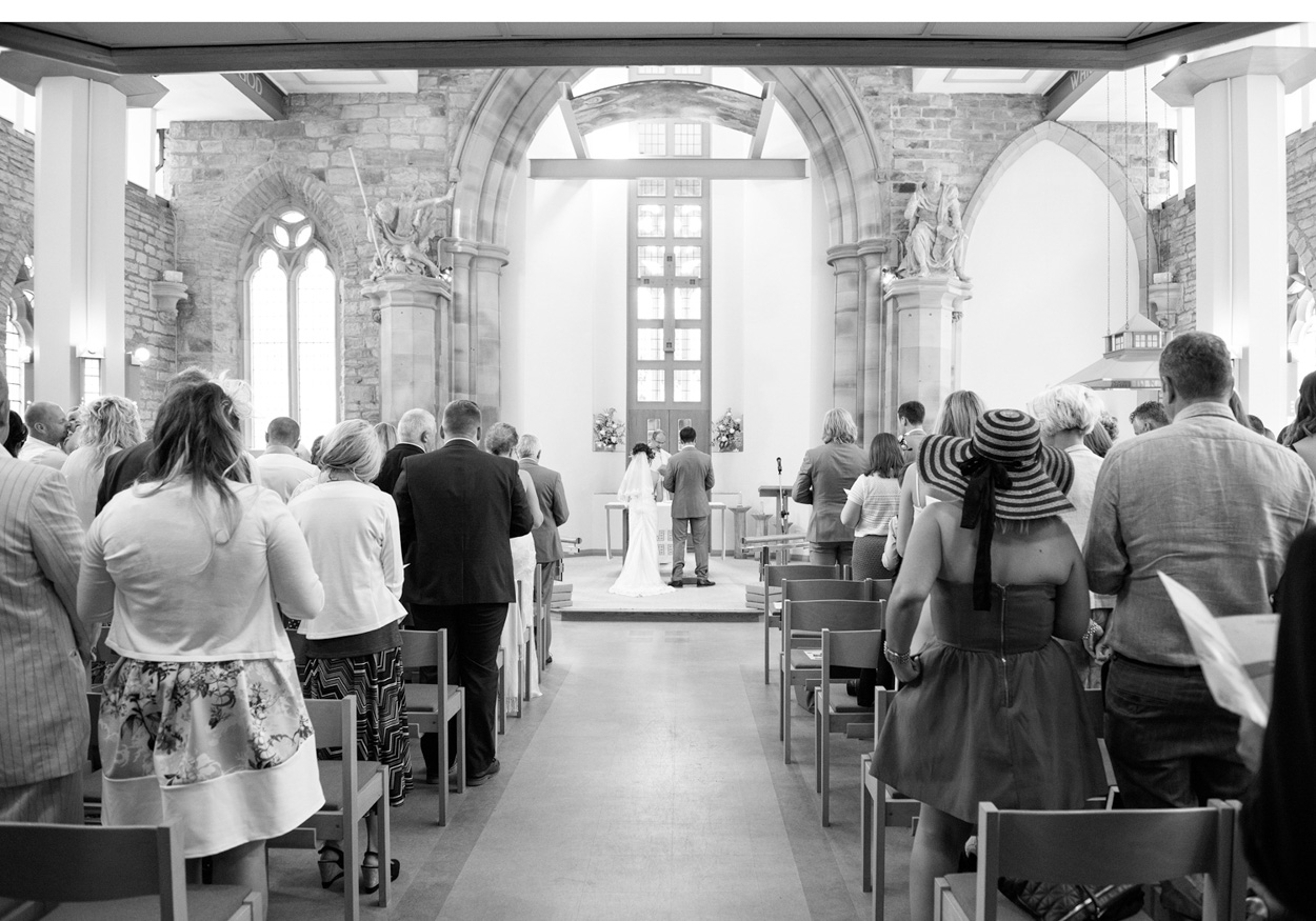 The couple share a kiss on a shaded path beside the church in natural contrast.