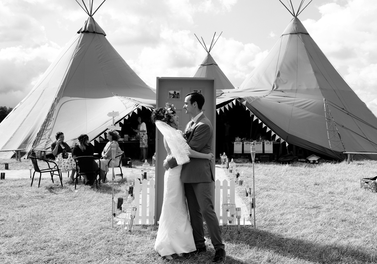 Larger group poses around the photo frame outside the tent in celebration.