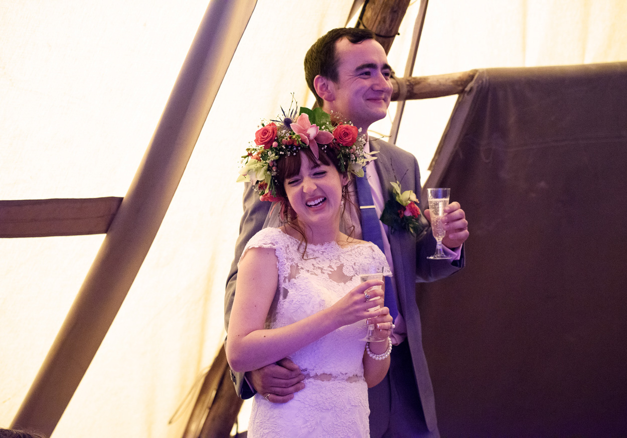 Bride and groom share a taste of their wedding cheesecake and smile.