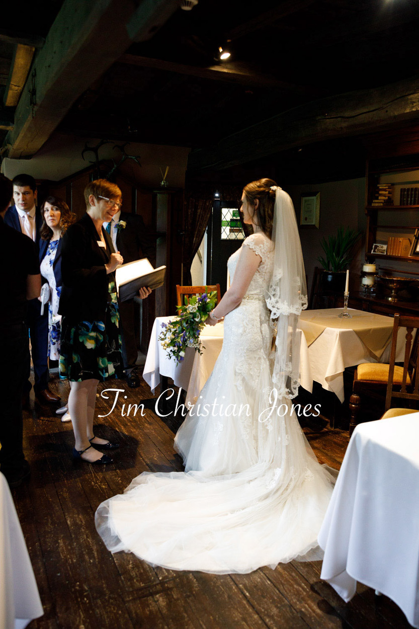 The wood floors and walls contrast the bride speaking with the registrar at her Priests House wedding
