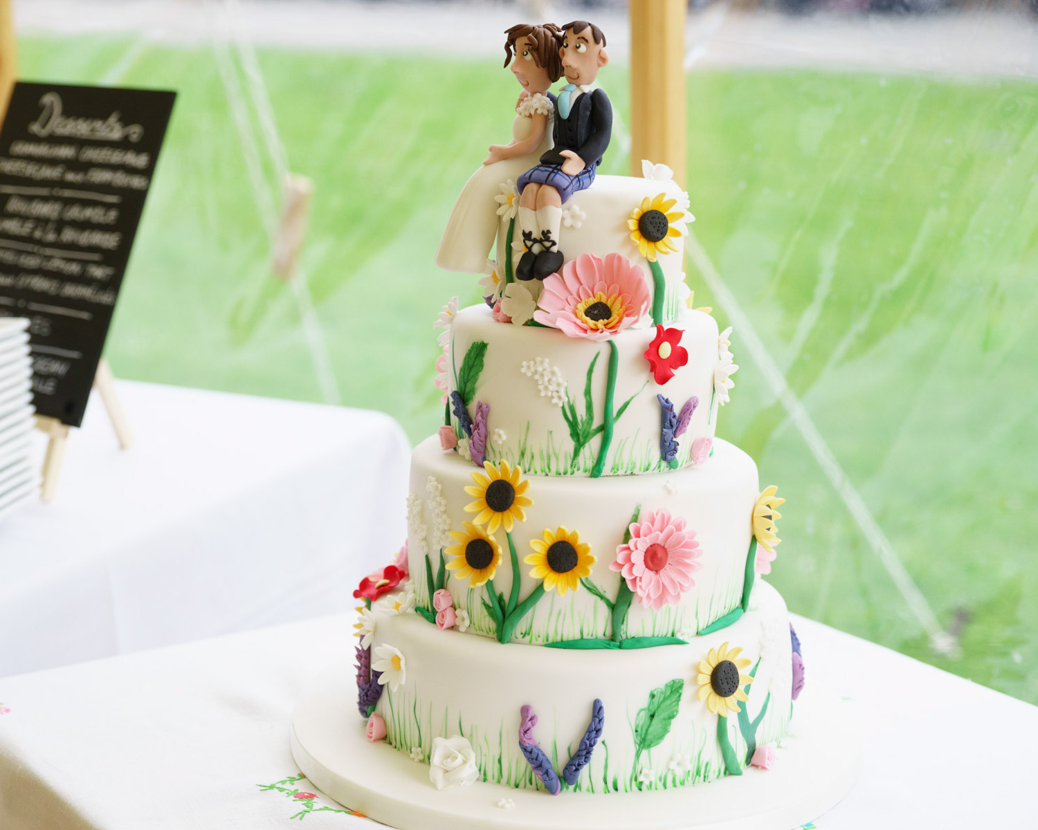 Wedding cake with floral decorations in a soft marquee glow, unedited and true to colour.